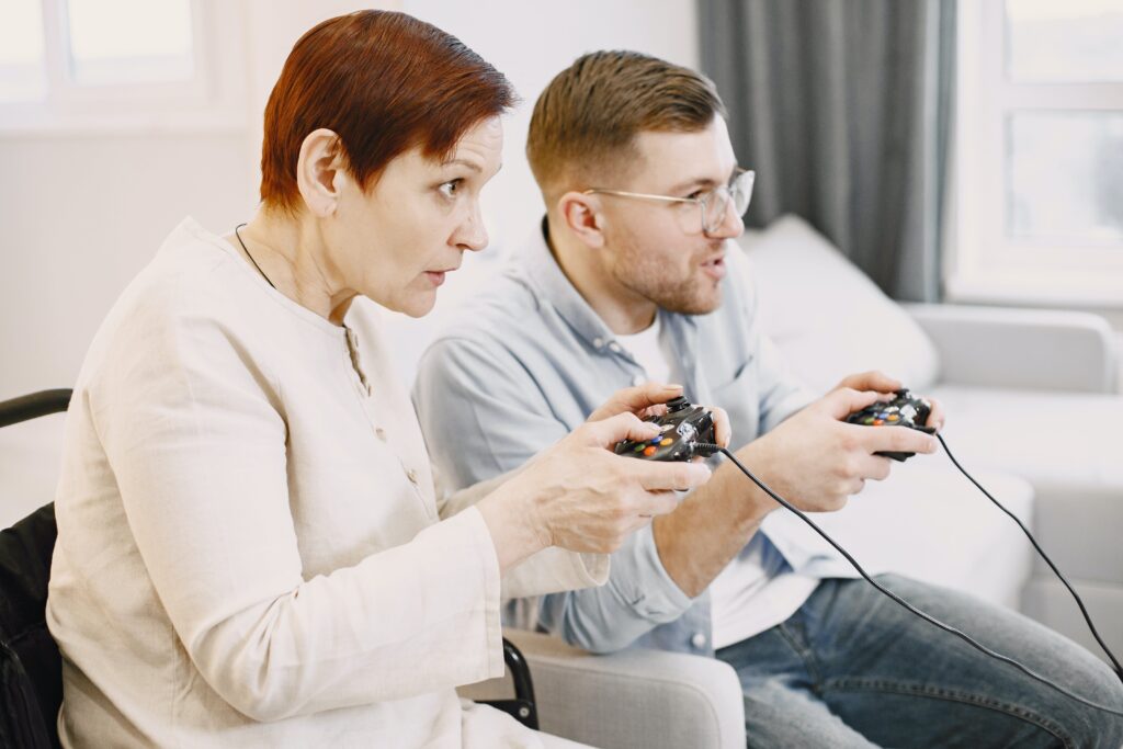 Man and woman sitting on a couch, holding Xbox controllers, looking off towards the side of the image with focused looks on their faces.